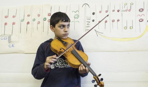 „MitMachMusik“in Berlin: Dieser Junge lernt mit dem fremden Instrument eine neue Kultur kennen. Foto: Christophe Gateau