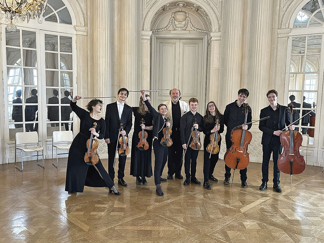 Acht schwarzgekleidete junge Musiker*innen Streicher*innen im Saal vom Schloss Solitude. Professor Schoneweg im hellen Sakko in der Mitte.