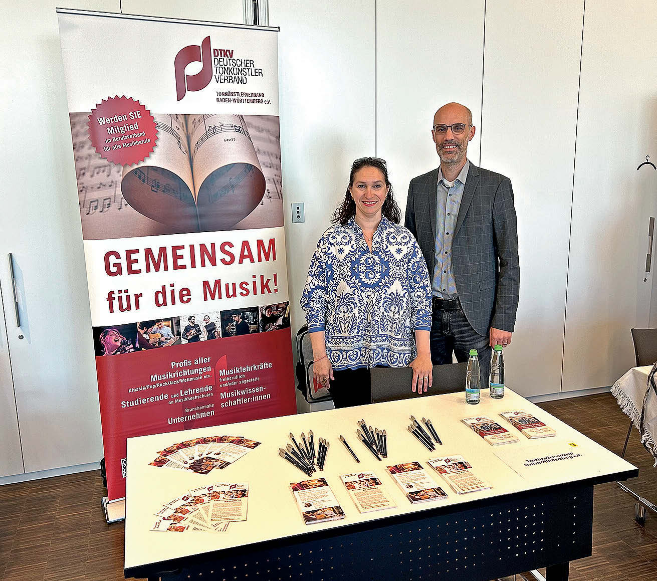 Zwei Menschen hinter einem kleinen Messestand des DTKV.