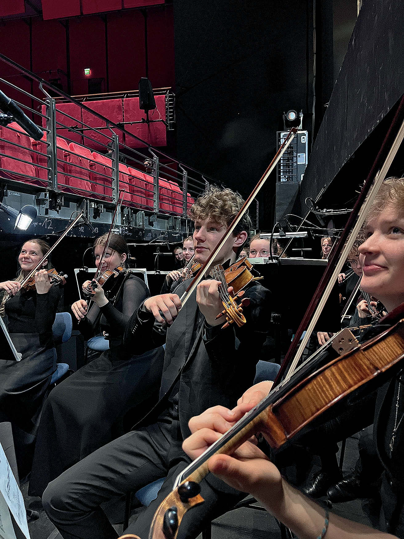 Nahaufnahme in die Violinist:innen eines jungen Geigenregisters hinein.