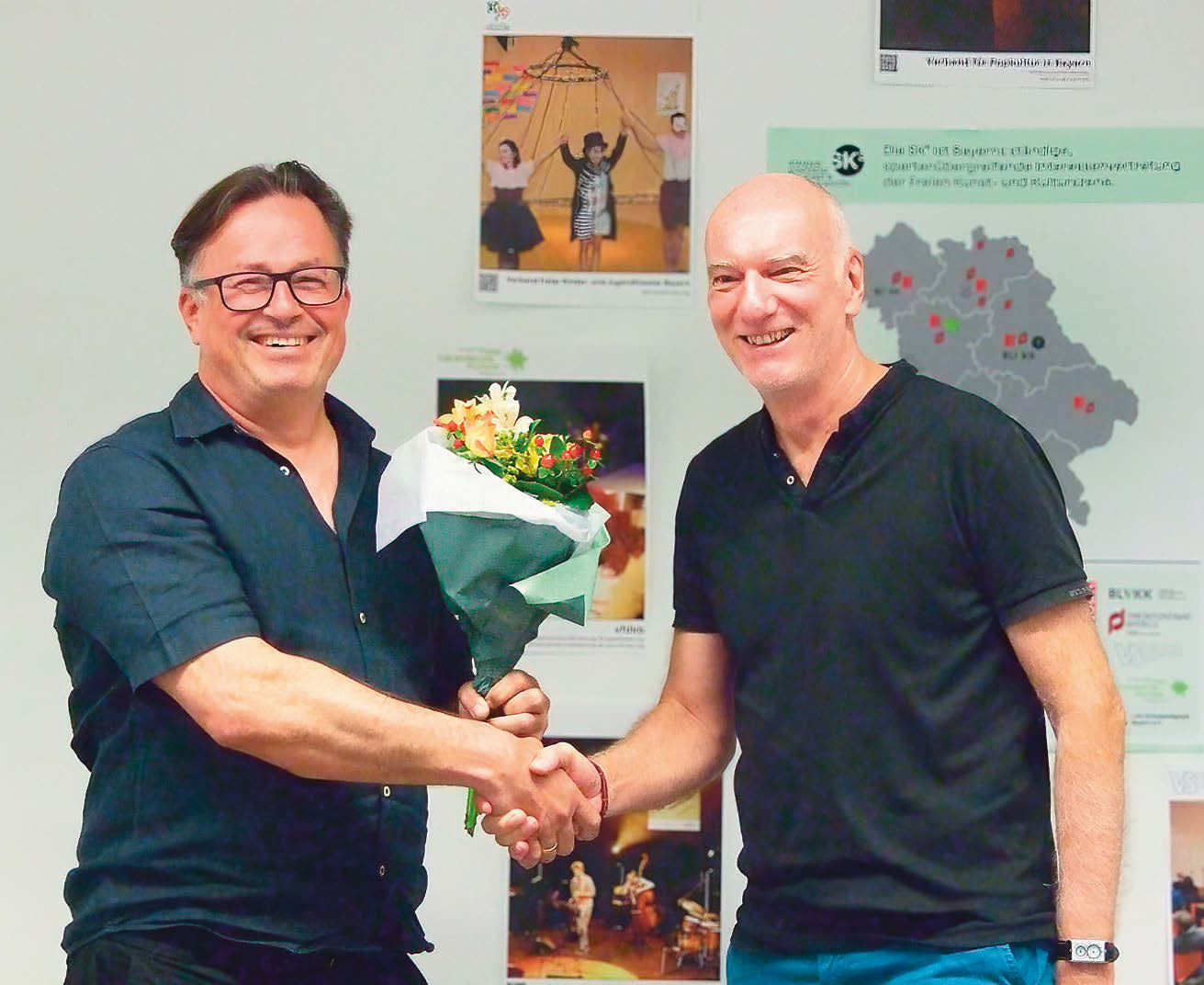 Der glatzköpfige Walter Heun verabschiedet Christian Schnurer (kurze schwarze Haare) mit Händedruck und Blumenstrauß.