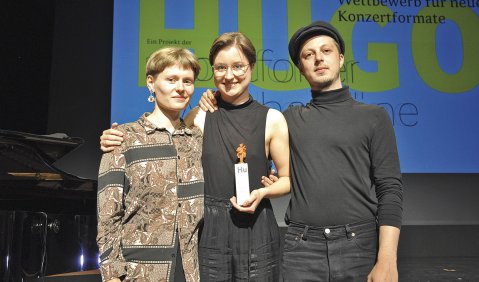 Das Ensemble TRI:UTOPIE erspielte sich den Hugo 2022 (v.l.): Magdalena Lorenz, Nina Gurol und Louis Voelkel. Die Trophäe zeigt, stilisiert, den namensgebenden Minnesänger Hugo von Montfort (1357–1423). Foto: Claudia Irle-Utsch