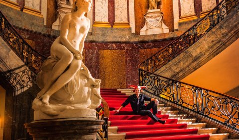 Tansel Akzeybek, mit Narrenkappe im Foyertreppenhaus des Bode-Museums. Foto: Jan Windszus Photography