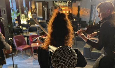 Das Foto zeigt die Bühne aus Perspektive hinter einem Gesangsmikrofon. Im Vordergrund stehen zwei Streicher, dahinter der  während des Soundchecks noch leere Zuschauerraum.