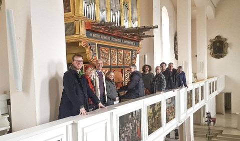 In der weiß gestrichenen Kirche steht eine Reihe von Leuten vor der spanischen Orgel.