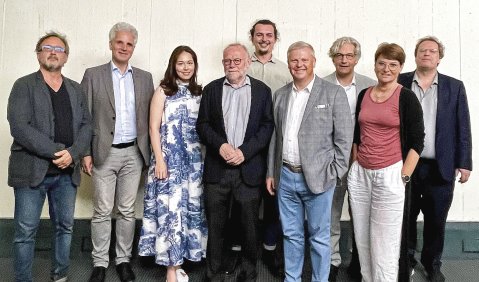 Die Menschen stehen vor einer weißen Wand zum Foto aufgestellt.