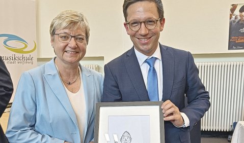 Frauke Heiligenstadt mit kurzen hellen Haaren und blauem Blazer und Falko Mohrs im bauen Anzug mit einem gezeichneten Sams-Gruß von Paul Maar.