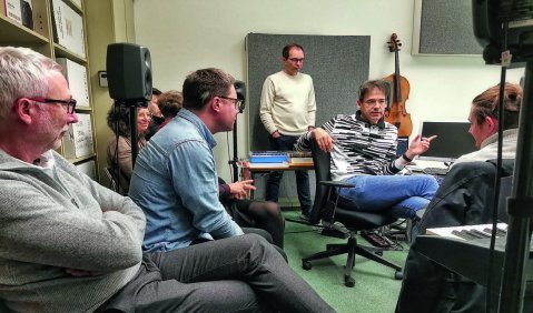 Ein Studio bzw. Musikseminarzimmer, eng besetzt von einigen Männern mittleren Alters im Gespräch. Das Foto zeigt nur einen kleinen Ausschnitt des Raumes.