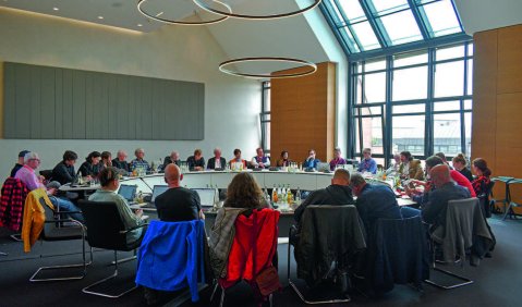 Ein runder Tisch (etwa 5 Meter im Durchmesser) mit einigen Komponist*innen daran.