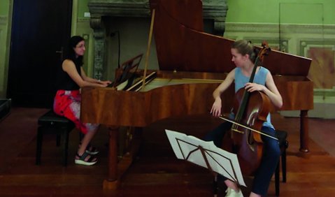 Ein Duo aus Cello und Klavier vor einem Kamin in einem italienischen Salon.