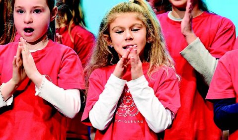 Singende und klatschende Kinder in roten T-Shirts