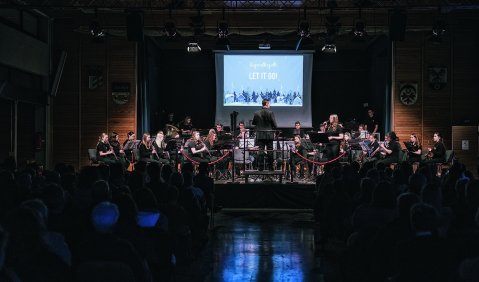 Ein Orchesterkonzert in dunklem Saal mit Projektion an der Rückwand hinter dem Orchester