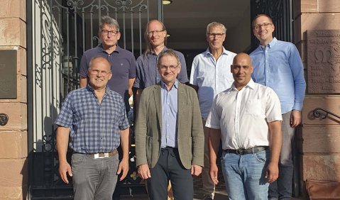 Die Gruppe steht im Sonnenschein auf der Treppe zu einem alten Rathaus.