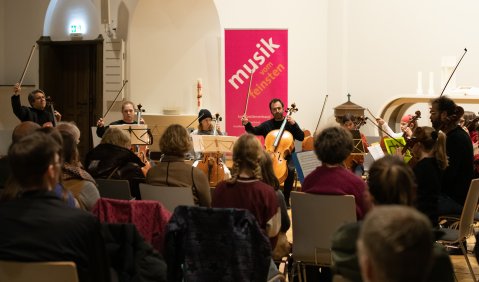 Ein Celloensemble mit Mitgliedern verschiedenster Alterstufen spielt ein Konzert.