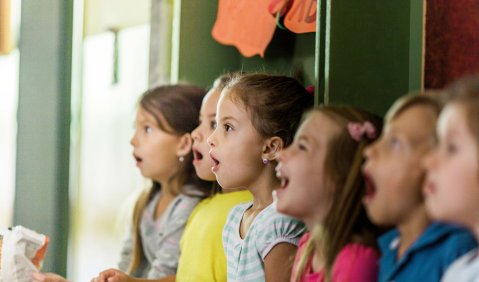 Eine Reihe von Kindern, die an der Wand stehen und singen.