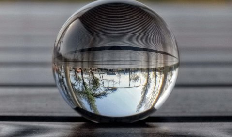 Ein Foto einer Glaskugel, durch die die Welt hinter ihr gespiegelt gebogen in ihr sichtbar wird.