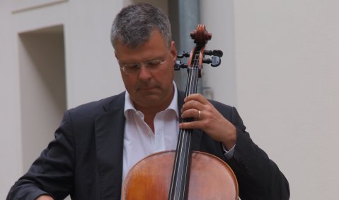 Höppner mit kurzem grauen Haar im Anzug am Cello