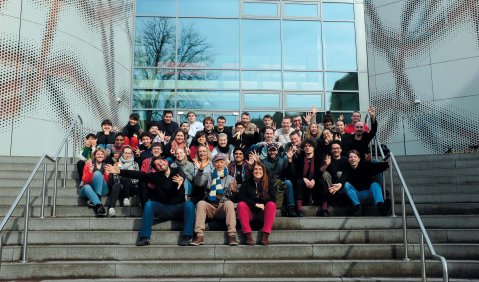 Ein Gruppenfoto eines Seminars auf einer breiten Treppe vor einem Gebäude mit Glasfront.