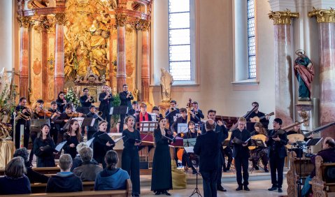 Chorkonzert mit ornamentstarkem Altar im Hintergrund.
