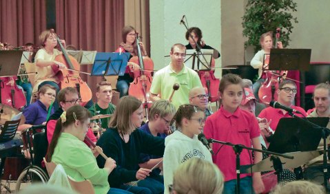 Mehrere Menschen unterschiedlichster Erscheinung musizieren und singen zusammen.