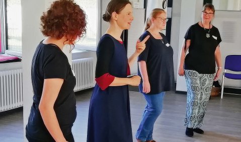 Vier Frauen tanzen in einer Reihe in einem Tanzstudio.