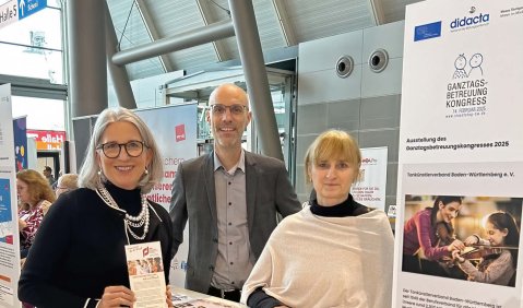Drei Menschen an einem Messestand.