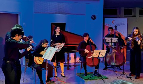 Ein primär blaues Bild (wohl aufgrund blauer Bühnenbeleuchtung) aus derem Dunkel das Barockensemble hervorsticht.