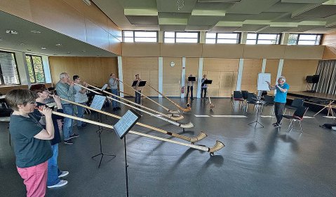 Viele Alphorbläser:innen in einem geräumigen Seminarraum.