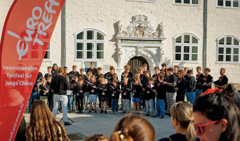 Ein gemischter Chor vor historischer Kulisse.