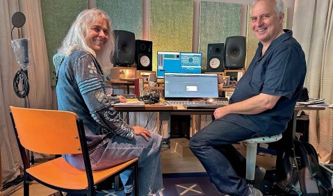 Zwei Personen (eine Frau und ein Mann) beide im höheren mittleren Alter am Computer im Hörraum eines Tonstudios.