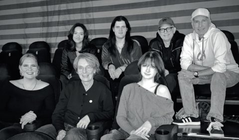 Ein Schwarzwei&szlig;bild von teils erwachsenen teils jugendlichen Menschen auf Kinosesseln.