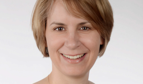 Eine blonde Frau in mittlerem Alter lächelt in die Kamera.