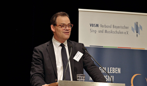 Ein Mann mittleren Alters im Anzug hält eine Rede.