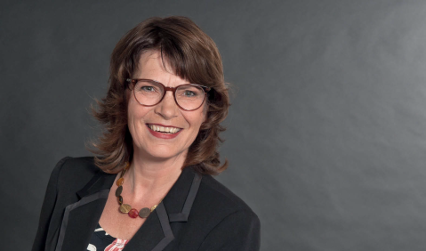 Eine Frau mittleren Alters mit braunen Haaren und Brille.