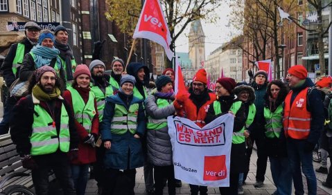 Eine Streikgruppe in Warnwesten mit roten ver.di-Fahnen.