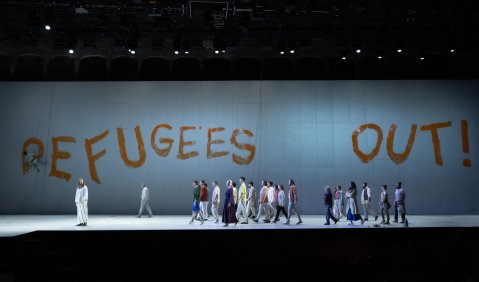 "Refugees Out!" prangt in großen Buchstaben über dem bunt gekleideten mutlos daherziehenden Ensemble.