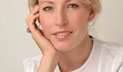 Ein Frau jungen mittleren Alters mit bloden Haaren und weißem Oberteil.