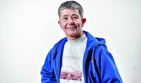 Portrait von Beate Maria Schweisfurth, einer Frau mit kurzen grauen Haaren, in blauer Sweatjacke und weißen Shirt.