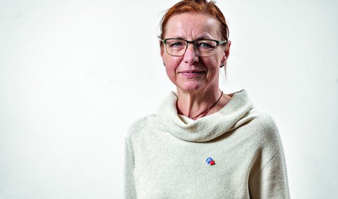 Portrait von Franziska Gröpl, einer rothaarigen Frau mit Brille und weißen Pullover.