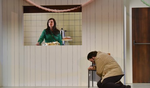 Charlotte (Boshana Milkov) schaut aus einem Fenster am kniend-verzweifelnden Werther (Mirko Roschkowski) vorbei. Stadttheater Bremerhaven.