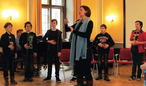 Mitglieder des Staats- und Domchores Berlin mit der Stimmbildnerin Judith Kamphues im Vordergrund und seinem Leiter, Kai-Uwe Jirka, am Klavier. Foto: Uniklinikum Leipzig