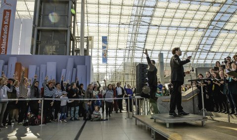 Klingender Messeschwerpunkt Litauen: Rechts singt der Messechor baltische Lieder – links animiert der MDR-Moderator die Zuhörer. 
