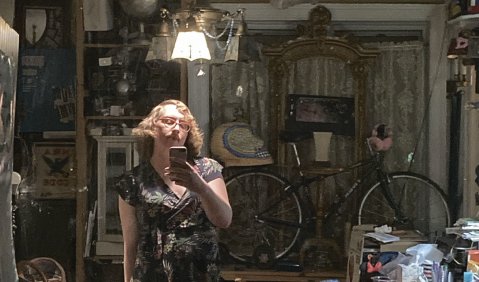 Marlene Bellissimo fotografiert sich selbst zwischen antiquarischem Mobiliar in einem Spiegel.