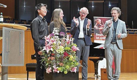 Alle vier beteiligten stehen auf der Bühne. Die Bühne ist mit Blumen geschmückt, die Stimmung heiter.