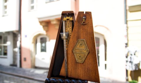 Ein historisches Metronom aus der Fabrikation Mälzels. Im Hintergrund sein Regensburger Geburtshaus Unter den Schwibbögen. Foto: Juan Martin Koch