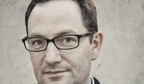 Gordon Kampe, in Jacke, hellem Hemd, mit dunklen kurzen Haaren, ohne Bart und mit schmaler Brille