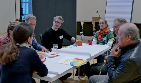 Mehrere Personen sitzen an einem Tisch zusammen und tauschen sich angeregt aus.