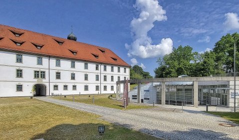 Ein altes Landschloss und ein etwas in die Erde gebauter moderner Bungalo-ähnlicher Konzertsaal mit Glasfront