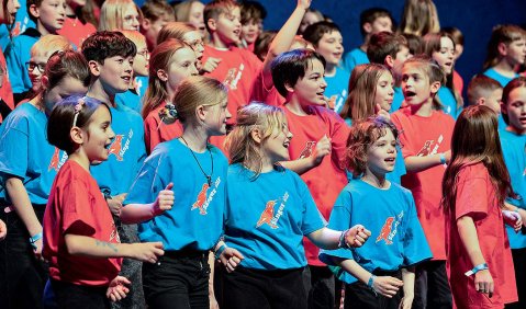 Ein Kinderchor mit Kindern, die rote und blaue T-Shirts tragen.