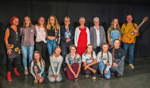 In verschiedenen Farben gekleidet stehen die jugendlichen und Erwachsenen beisammen.